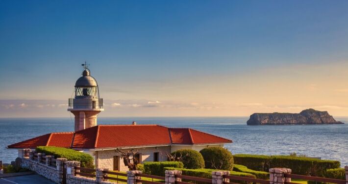 El faro de Suances al atardecer con la isla de los Conejos al fondo