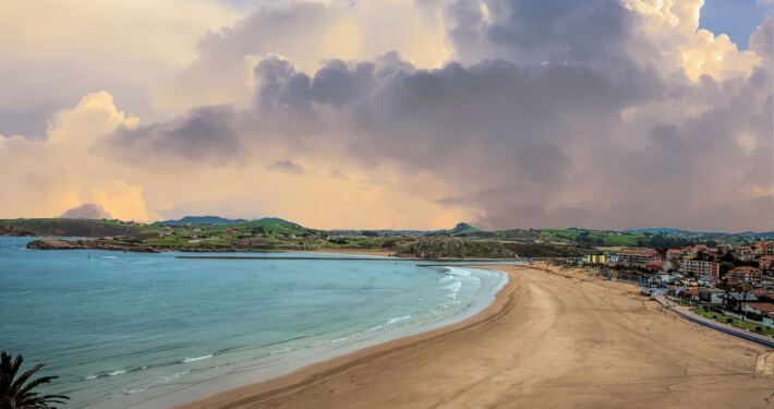 Playa de La Concha de Suances con cielo dramático y arena dorada